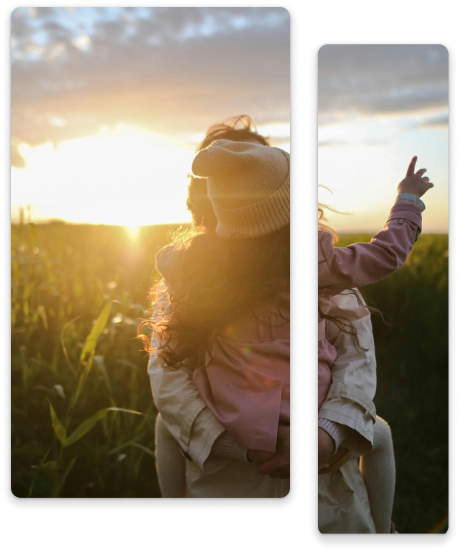 A young girl on someone's shoulders, pointing toward the sunset.